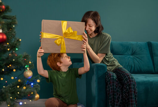 Mother and son hold a large Christmas gift at home