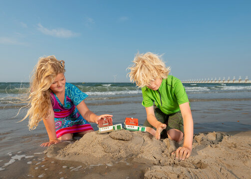Brother and sister playing with model houses on Dutch beach