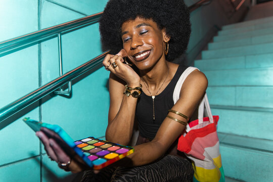 Nonbinary person applies makeup on subway stairs in Barcelona