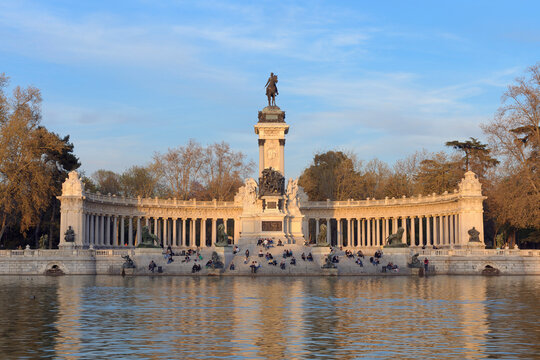 The Retiro Park lake reflects the Alfonso XII Monument at sunset