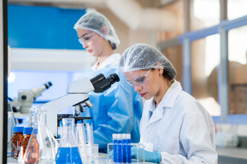 Professional female scientists working as a team in a sterile laboratory conducting advanced...