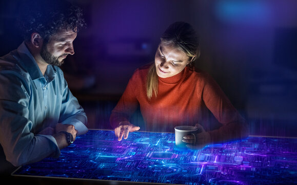 Man and woman analyze data on a glowing screen in the office