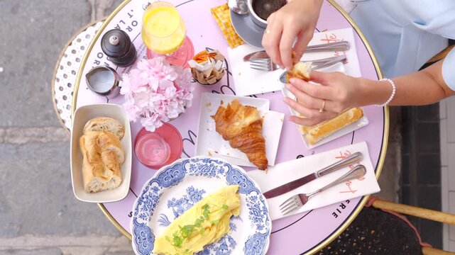Top view of woman tearing croissant at Paris cafe breakfast
