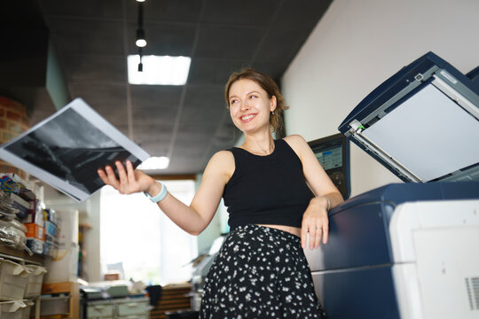 Smiling woman holds a photograph at the print shop