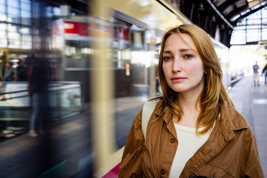 Woman waits on a train platform in Berlin as a train rushes by