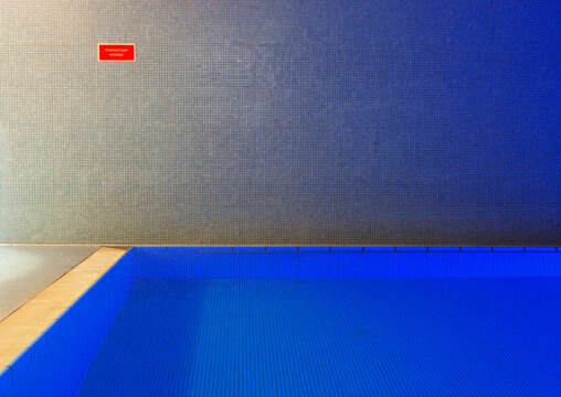 Empty indoor swimming pool with sign at the wall
