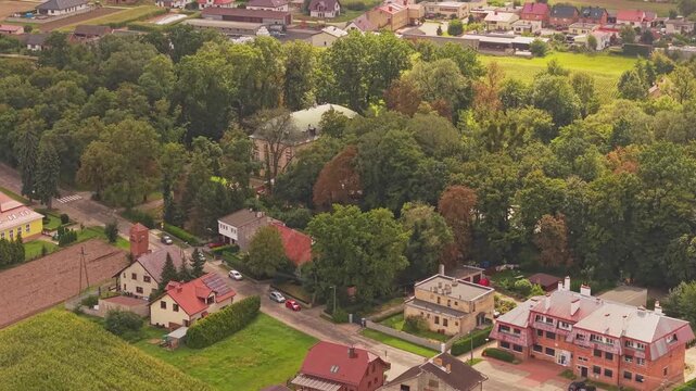 Aerial view of Palac w Pakoslawiu surrounded by residential houses, lush trees, and agricultural fields in Nowy Tomysl, Wielkopolskie, Poland.