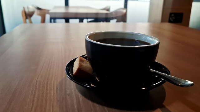 A barista serving a freshly brewed cup of black coffee on a rustic wooden table inside a cozy cafe, capturing the warm atmosphere of cafe culture and the experience of enjoying freshly made coffee. 