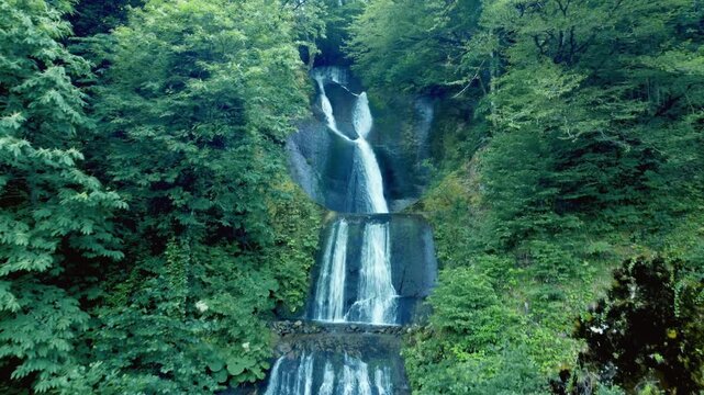 The impressive Kevin Mountain Waterfall, flowing down rocky ledges into a clear stream, surrounded by dense green forest and lush summer foliage in the calm, picturesque wilderness of Georgia