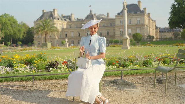 Woman in white hat relaxing before Luxembourg Palace in Paris