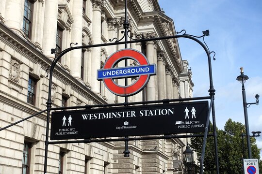An ornate entrance sign for Westminster Station on the London Underground, featuring the iconic red-and-blue roundel against classic stone architecture.