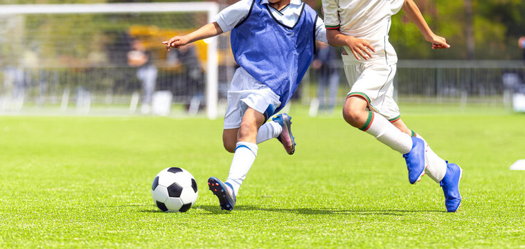 Kids as Football Soccer Players Running with Ball. Footballers Kicking Play League Match During Sunny Day. Two Teams in Sport Competition. Teenage Soccer Players Running in a Duel and Kicking Ball