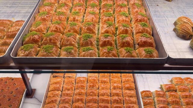 Assortment of traditional Turkish baklava pastries displayed in a glass shop window in Istanbul, Turkey. 