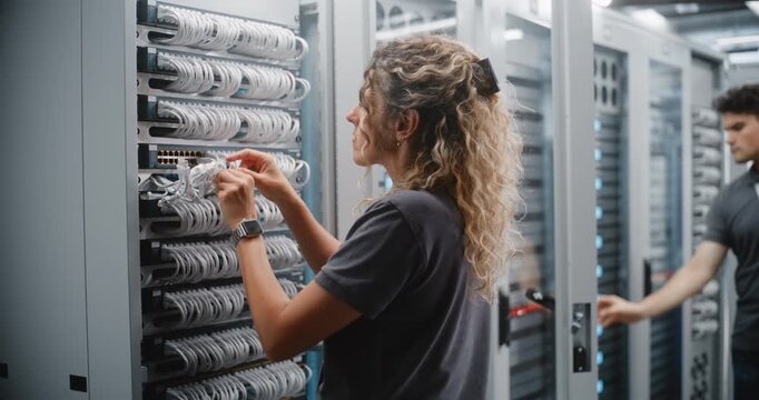 Female Network Engineer Connects Ethernet Patch Cables to Rack Mounted Network Switch, Organizing Structured Cabling in Modern Data Center For Reliable Connectivity, Efficient Routing and Maintenance.