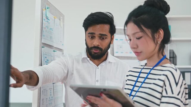 Indian male team leader standing and explaining a strategic plan to a female colleague
