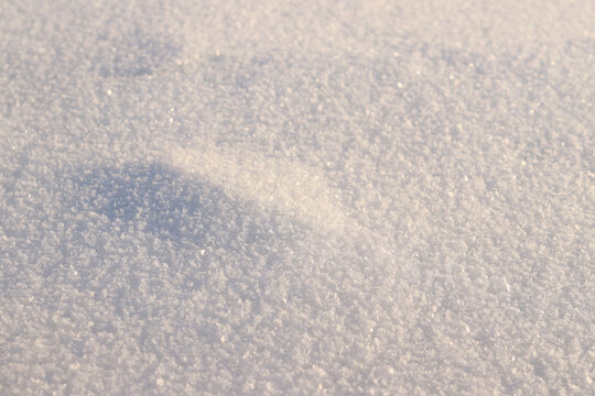 exture of fresh loose snow in sunlight close-up. Macro photography of clean snow surface, texture of white snow, winter abstract background, snowy surface with natural crystal structure. Winter
