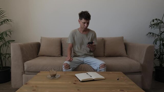 Problem solving and decision making at home, man checks unexpected information on smartphone, pauses for coffee and thinks before returning to phone to consider what to do next