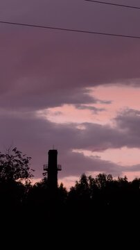 Distant Tower and Tree Silhouettes Beneath Soft Pink Sunset Clouds