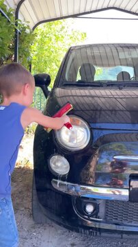 close-up video of boy carefully helping to wash the car with interest. concept of involving children in family chores, fostering helpfulness, and encouraging quality family time spent productively