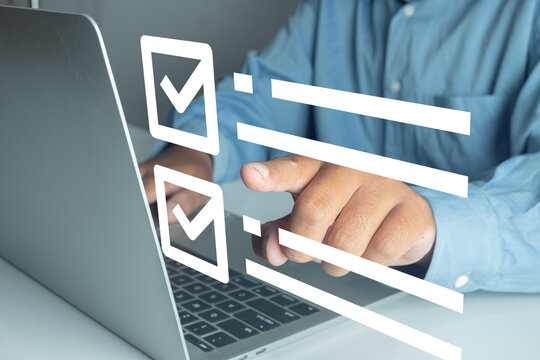 Man working on a laptop computer with a digital checklist graphic overlay. Concept of task management, online survey, goal planning, quality control, and completing a digital to do list.