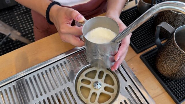 Close-up video of a barista steaming and frothing milk with a professional espresso machine for cappuccino, latte and other milk-based coffee drinks