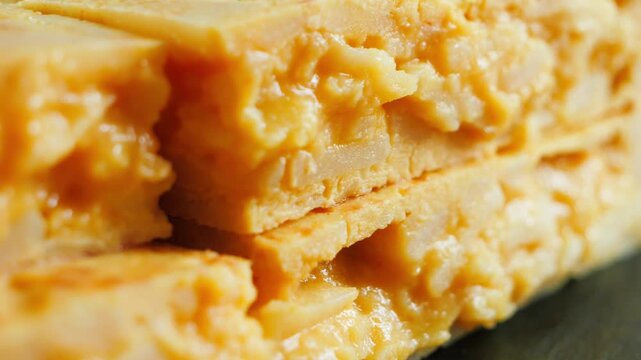 Close up of a juicy Spanish tortilla cut in half showing its soft potato and egg filling a traditional Spanish tapas dish. High quality 4k footage