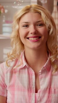 Happy smiling Caucasian teen girl touching face in pink bathroom looking at camera shy cheerful woman with soap bubbles self care skincare routine indoors beauty cosmetic procedure radiant fresh skin