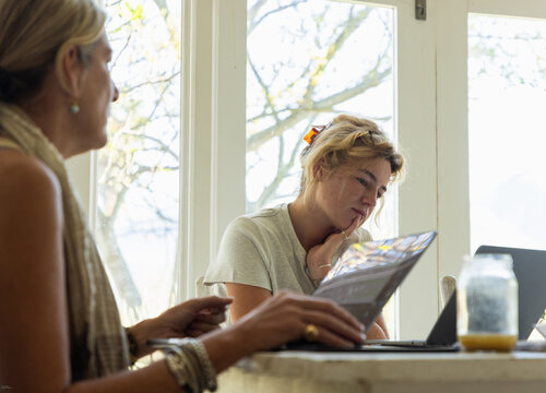 young woman and adult woman  working on laptops in light filled room