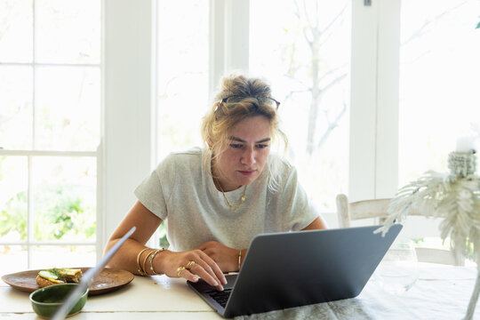 young woman working on laptop in light filled room
