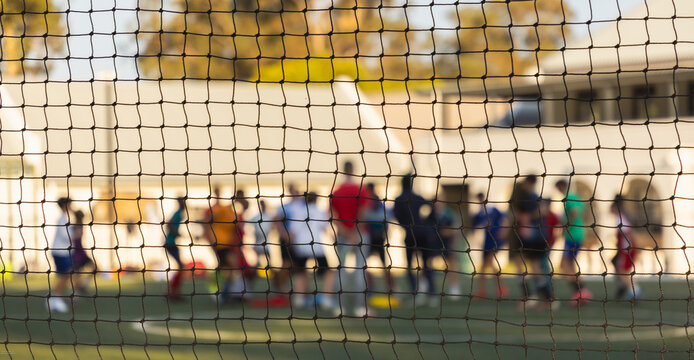 abstract view of soccer players out of focus from behind soccer net