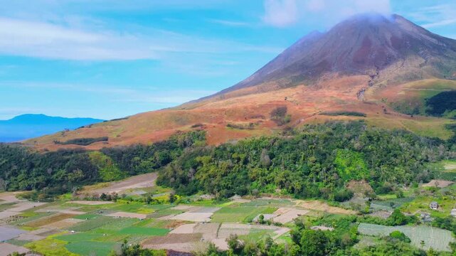 Aerial view of Mount Sinabung volcano with lush forests and agricultural fields in Naman Teran, North Sumatra, Indonesia.