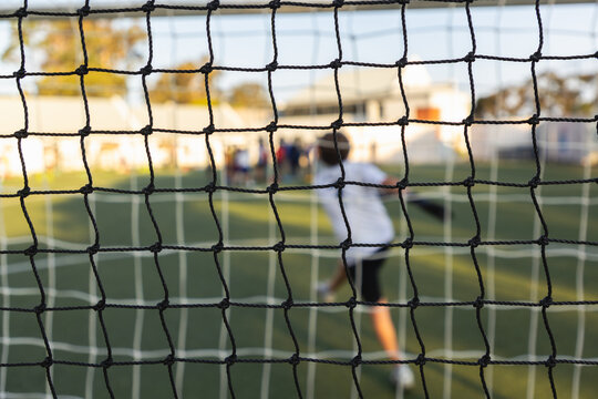 rear view of teenage goalie from behind the soccer net during game