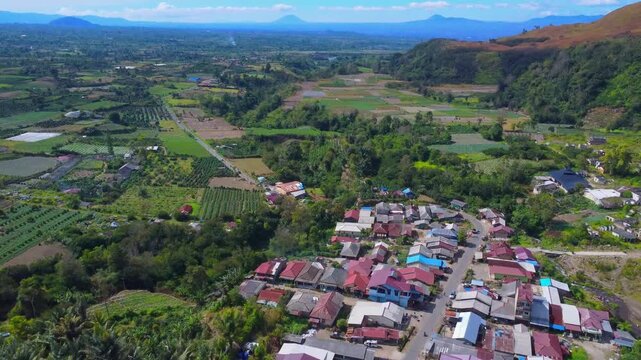 Aerial view of Mount Sinabung and the rural village of Naman Teran surrounded by lush agricultural fields and volcanic landscape in Naman Teran, North Sumatra, Indonesia.