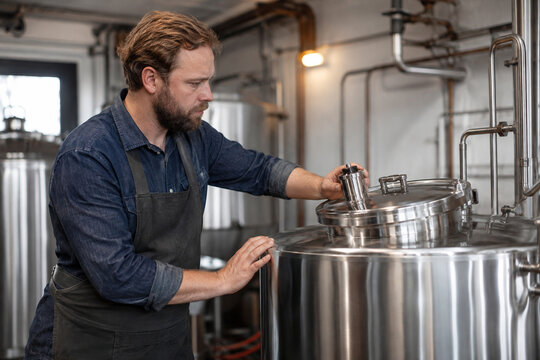 Craft brewer inspecting stainless steel production equipment