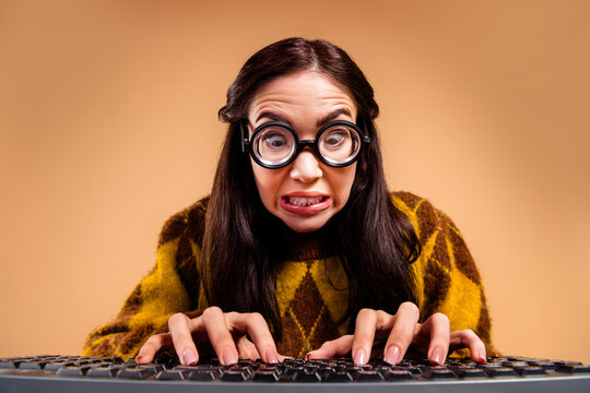 Nerdy woman with oversized glasses typing frantically on a keyboard, making a funny anxious face