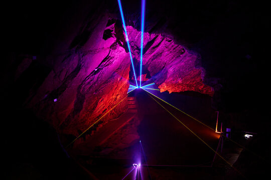 Ein weitl&auml;ufiger H&ouml;hlenraum der Drachenh&ouml;hle Syrau wird von roten, blauen, gr&uuml;nen und gelben Laserstrahlen sowie farbigem Licht durchzogen.