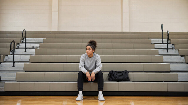 Isolated Teenage Athlete Sitting Alone on Empty Gym Bleachers