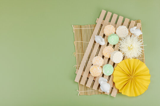 Traditional mooncakes on a wooden stand with ceramic rabbits, paper fan, chrysanthemum, bamboo mat