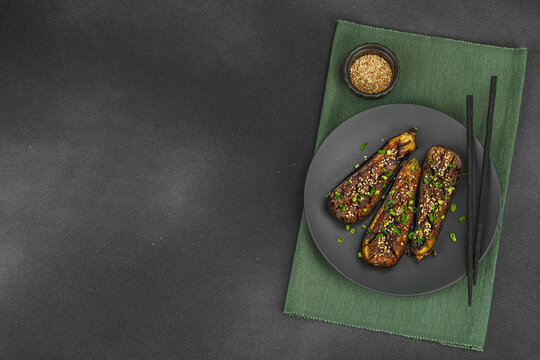 Miso glazed eggplant half with sesame seeds and green onion on a plate