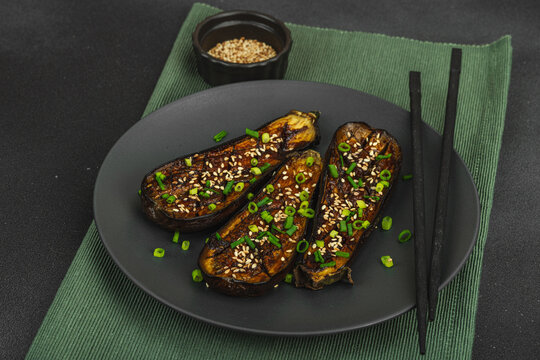 Miso glazed eggplant half with sesame seeds and green onion on a plate