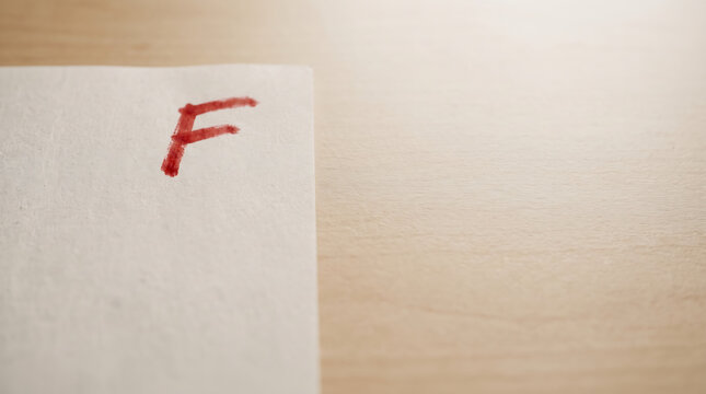 Exam paper with a red failing grade F written on it, representing school test failure, bad education performance, and low academic score