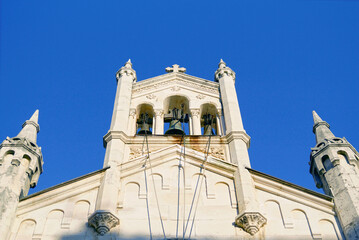 Fototapeta premium Stone belfry of Saint Michael Archangel church with ornate pinnacles on Belavista square, Herceg Novi. Captures architectural eclecticism, Byzantine influences, and multicultural heritage synthesis.