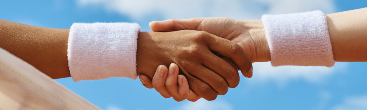 Close up of woman and man shaking hands over tennis net after match. Sportsmanship and partnership visual suitable for sports marketing and diversity campaigns