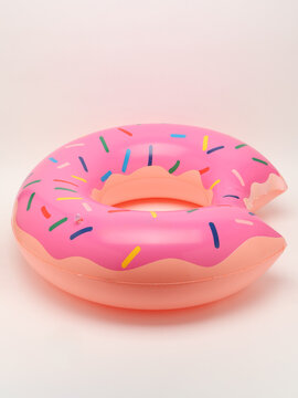 Inflatable pink bitten donut pool float with colorful sprinkles isolated on white background