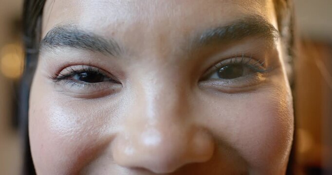Woman is leaning closer to lens, is initiating eyes narrowing and cheeks lifting in warm-lit room