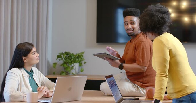 African American coworkers at meeting table, presenter tapping tablet, gesturing and seeking input