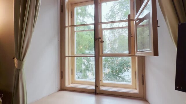 An open wooden window brings fresh air into a cozy historic room in Pushkin, Saint Petersburg. Green trees shine outside. The peaceful scene fills the space with calm nostalgia.