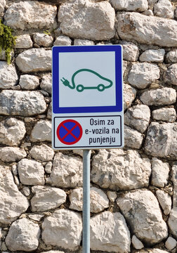 A road sign marks an electric vehicle charging zone with a text in Croatian stating that parking is forbidden except for e-vehicles while charging.