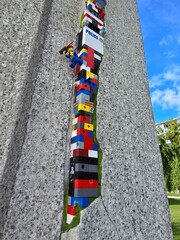 Fototapeta premium Lego dispatchwork street art in a cracked stone wall with police brick and climbing minifigure Sassnitz Ruegen Germany September 06 2025
