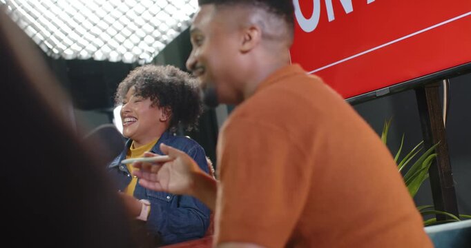 African American hosts man gesturing with stylus speaking woman laughing reflecting at studio mic